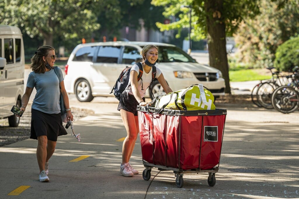 Incoming undergraduate Kate Dekanich and her mother push her essential belongings in a red cart towards Gilman House in Kronshage Residence Hall during the first day of move-in.