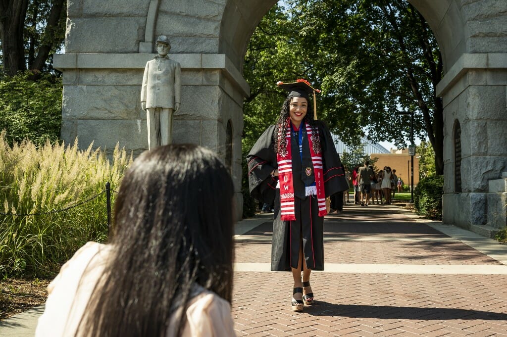 Person in cap and gown standing in front of arch
