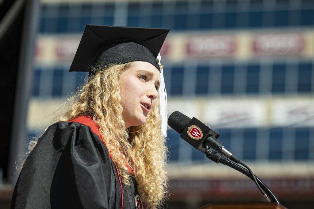 Person in cap and gown speaking into microphone