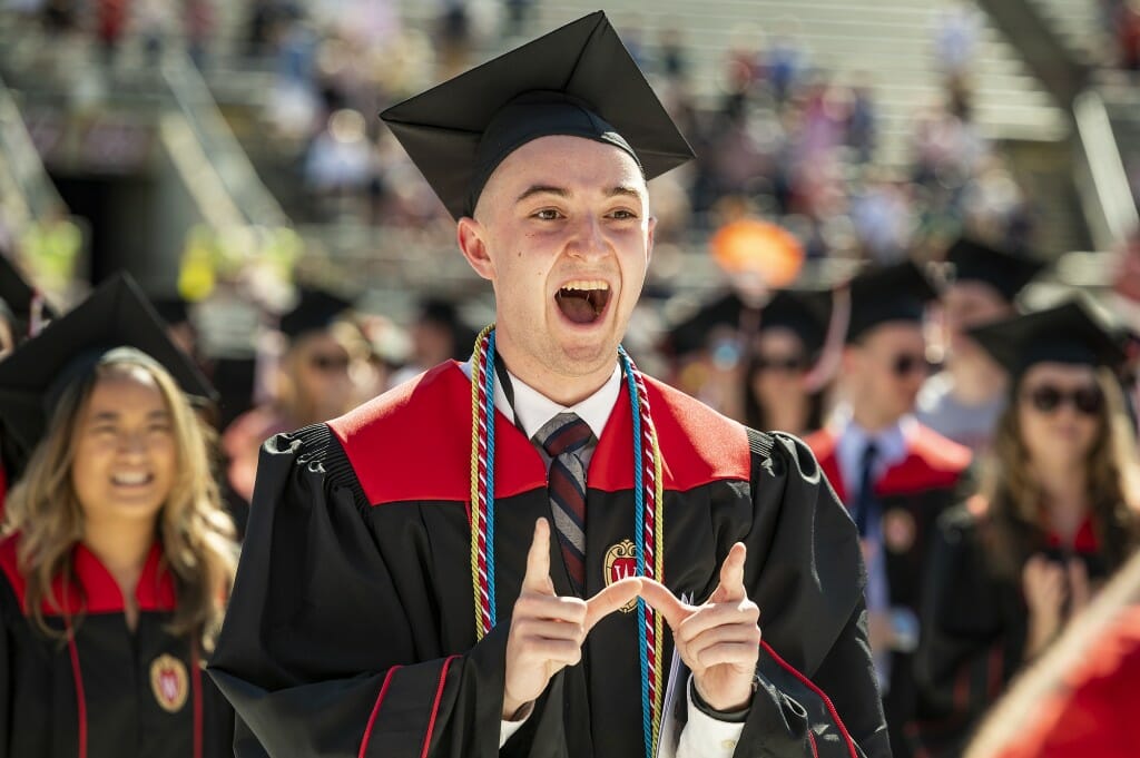 Person in cap and gown making a W with their fingers