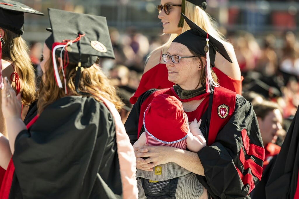 Person in cap and gown holding a baby