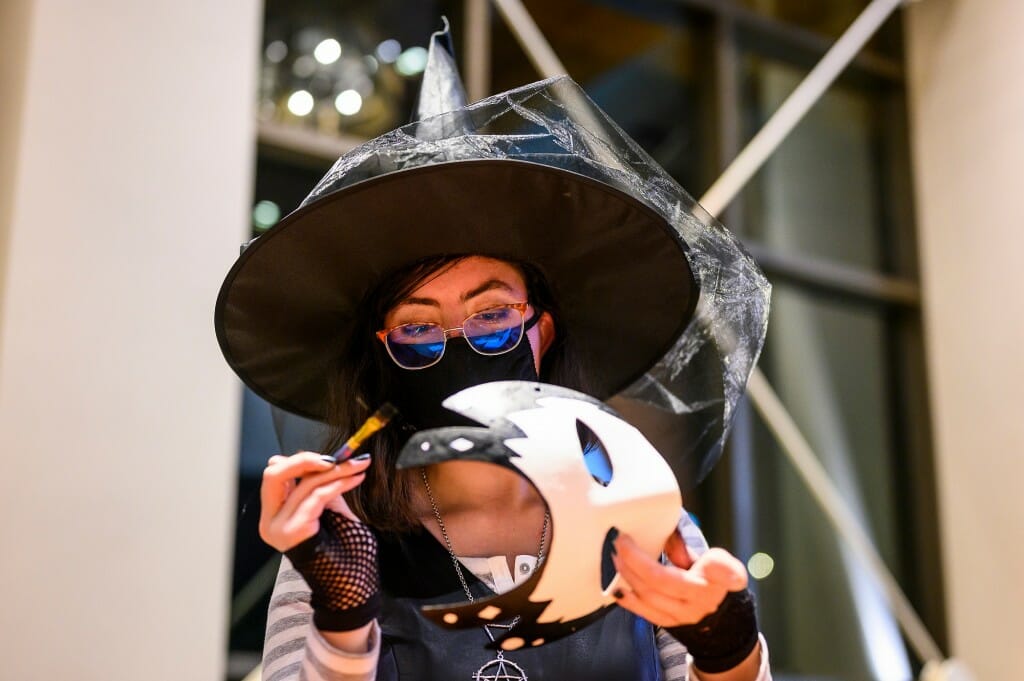 Dressed as a witch, first-year student Avery Morrison decorates a masquerade mask during the Halloween Bash.