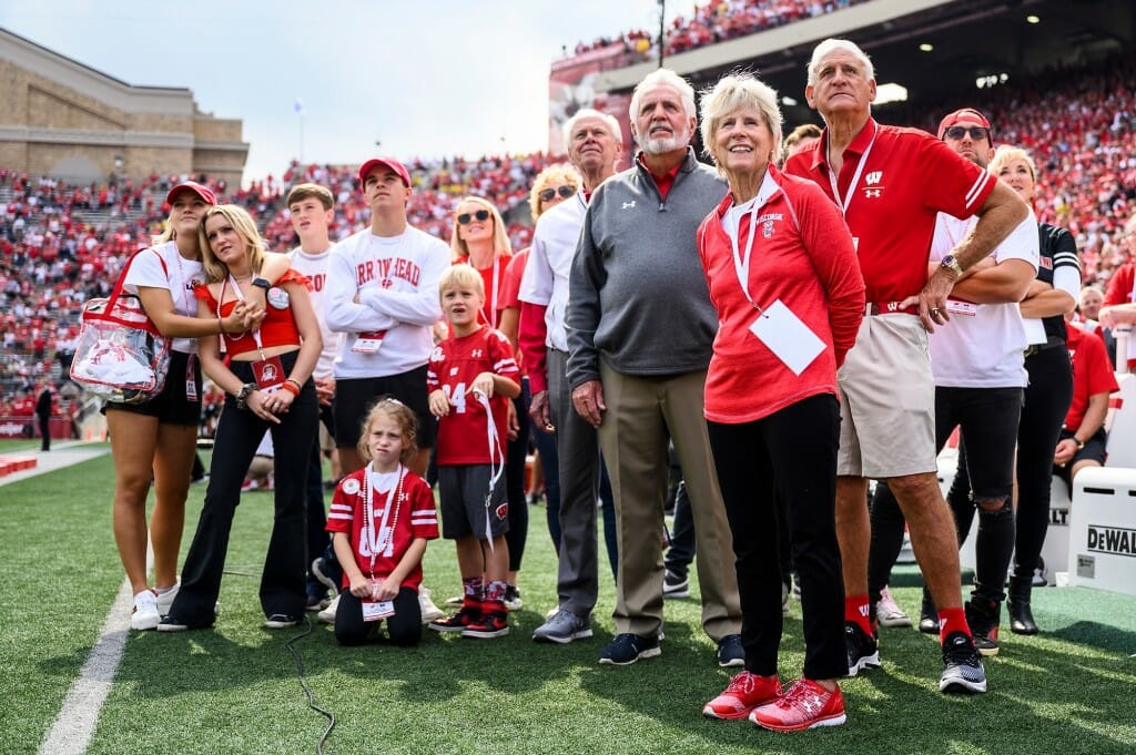Dignitaries and guests on the side line listen to a video announcement naming the field as Barry Alvarez Field at Camp Randall Stadium.