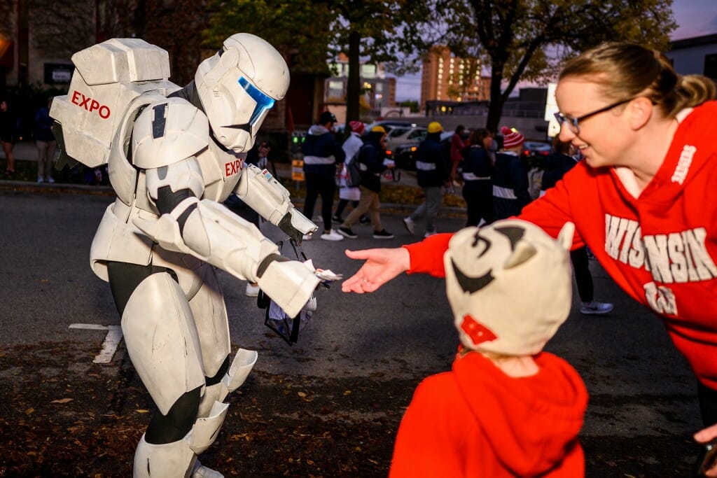 Noah Williams with Engineering Expo, dressed as a Star Wars Clone Trooper, hands out candy to a spectator. Williams made parts of the costume using a 3D printer.