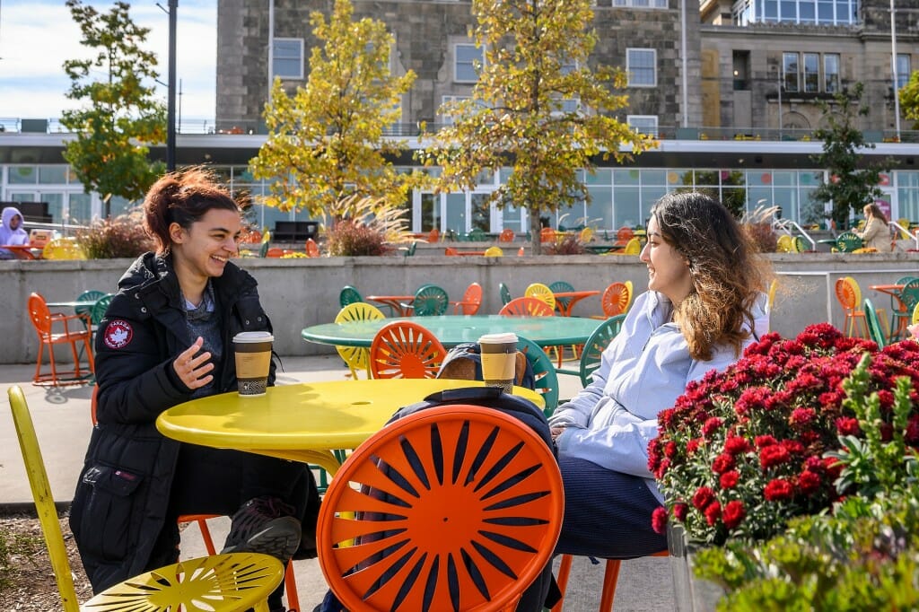 Conversing in Turkish — possibly about their history and computer science studies, but probably about something more lighthearted — graduate students Selenay Aydin (left) and Bengisu Cagiltay enjoy the Memorial Union Terrace.