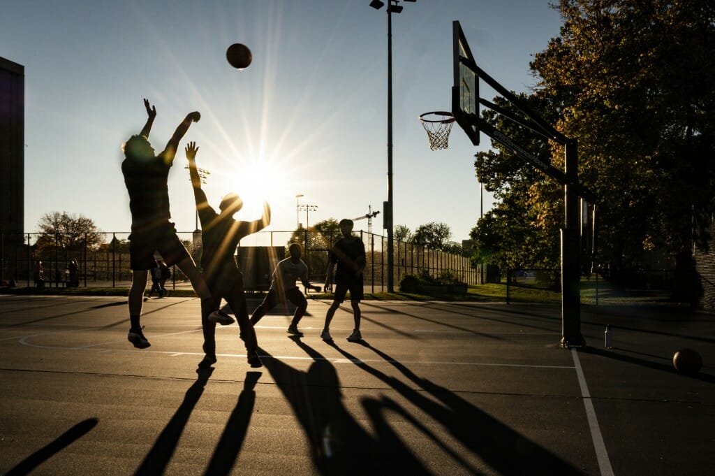 Long shadows extend like tall defenders from the silhouettes of students playing a pickup basketball game near the Lakeshore Neighborhood residence halls. 