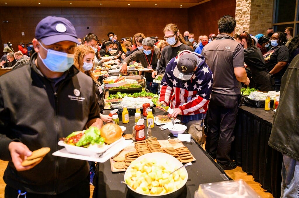 Attendees select tailgate-style food from a catered buffet line.