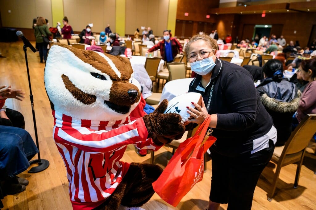 Bucky Badger offers a football to Guadalupe Jensen, a second-shift custodian lead for Gordon Dining and Event Center.