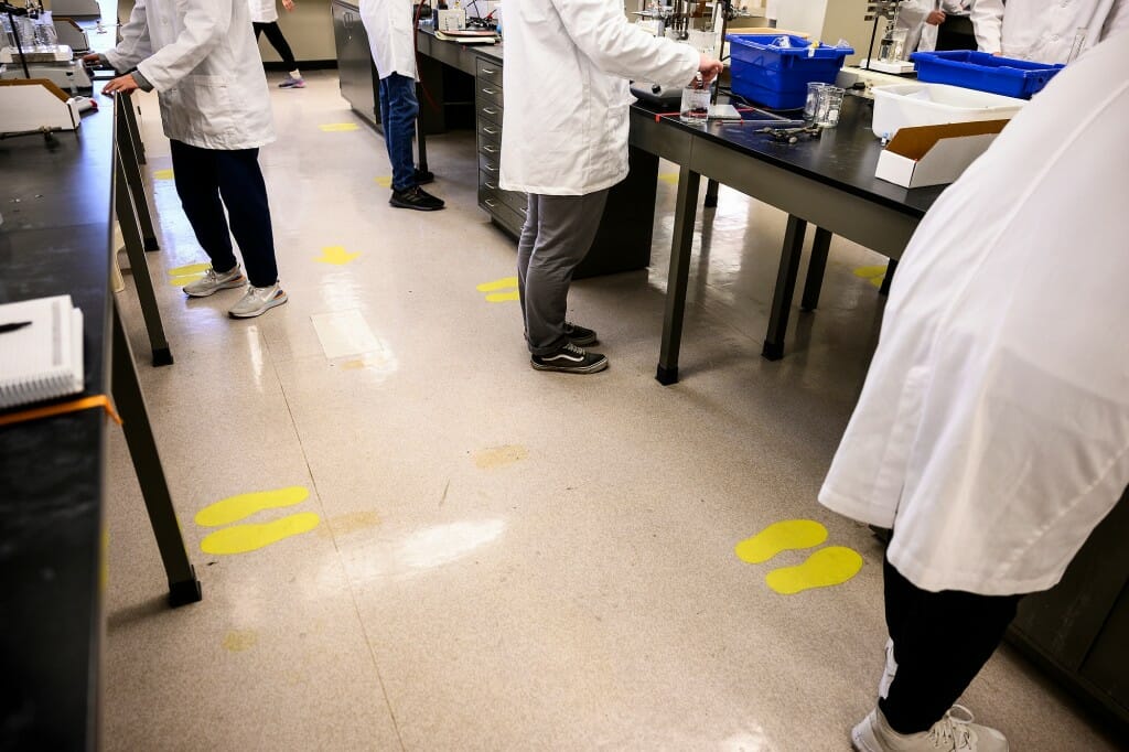 Yellow shoe shapes mark the floor of a lab where students are supposed to be standing