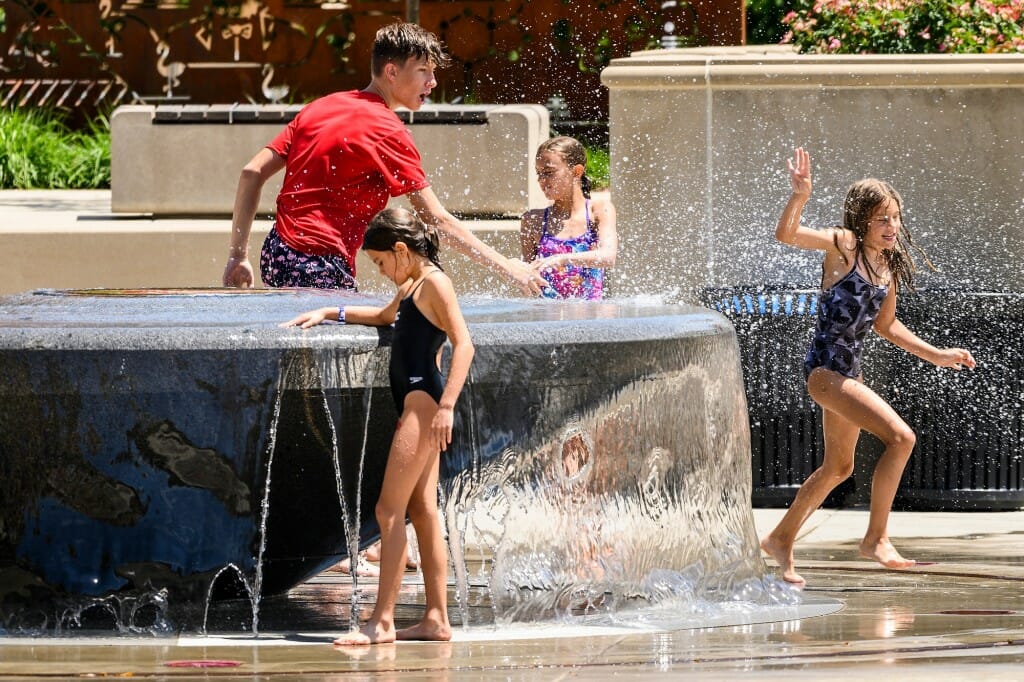Several children splashing in water flowing from a fountain
