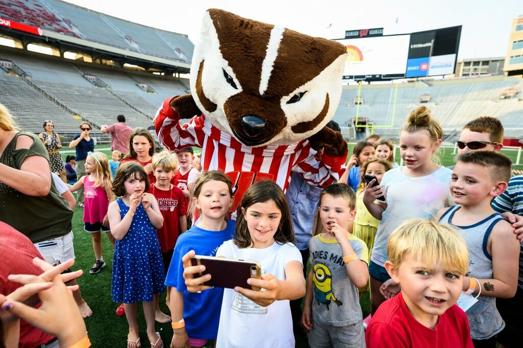 A large group of children gathering around Bucky Badger for a selfie