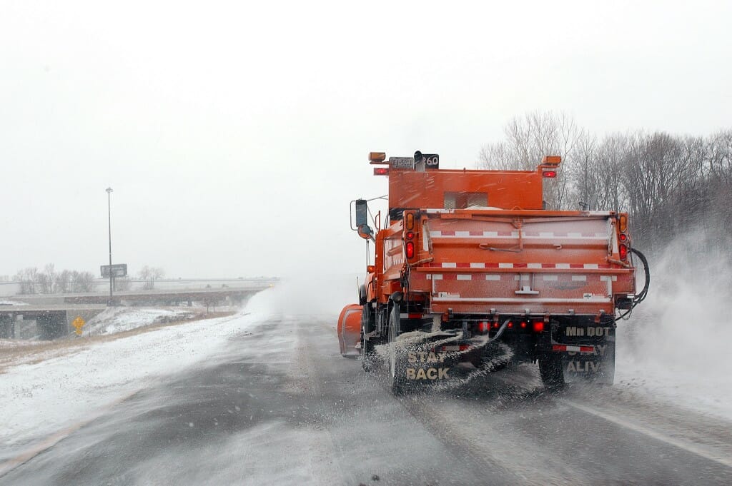 A snow plow truck spreading salt on a highway