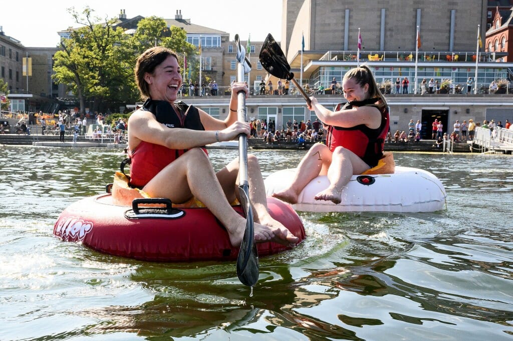 Two people paddling in large pumpkins floating in inner tubes on Lake Mendota