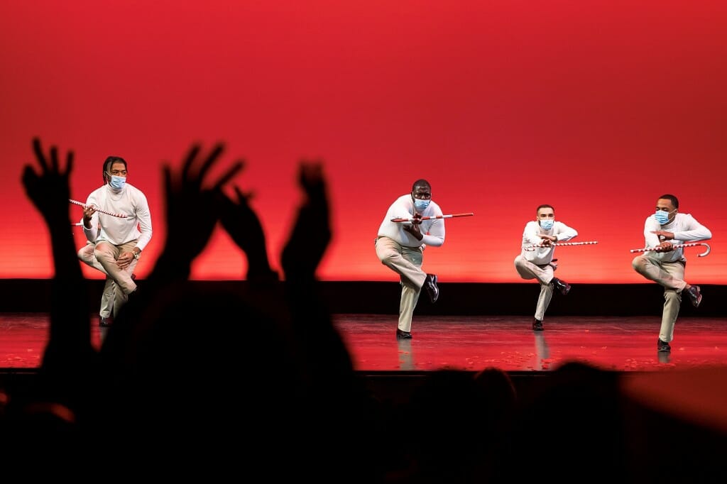 Students performing a dane number on a stage with red lights