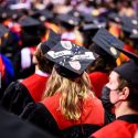 A shot behind of a crowd of UW students in commencement regalia.