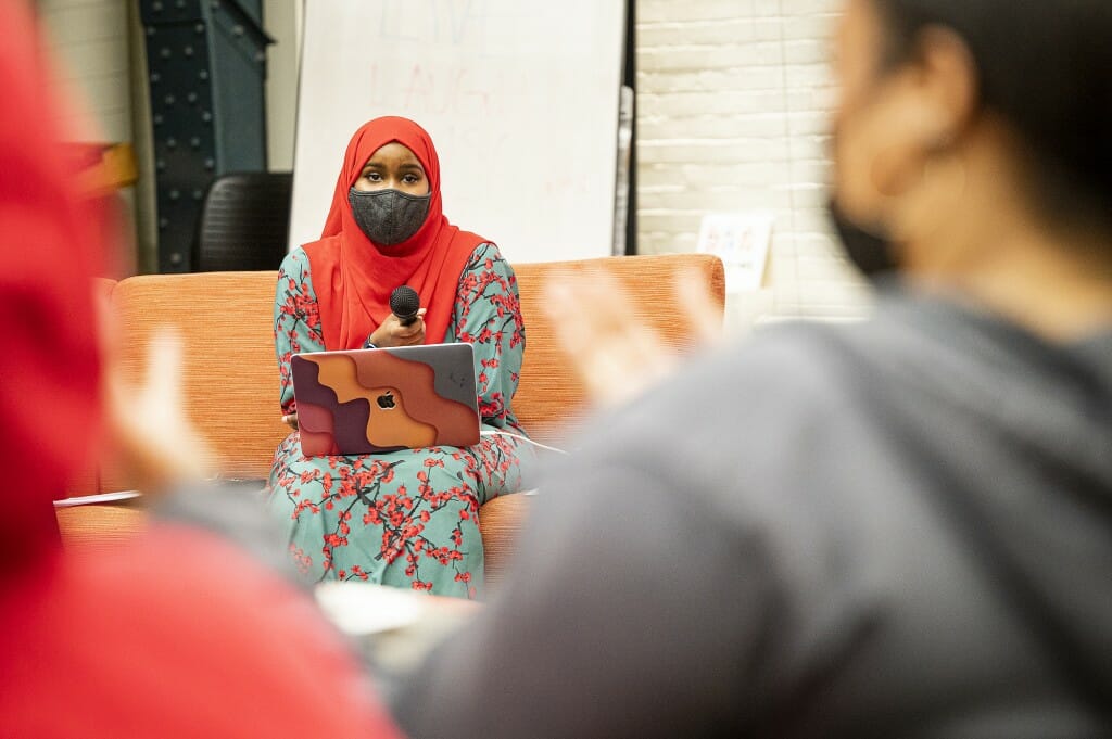 Student and discussion panel member Yasmin Nur listens to audience reaction.