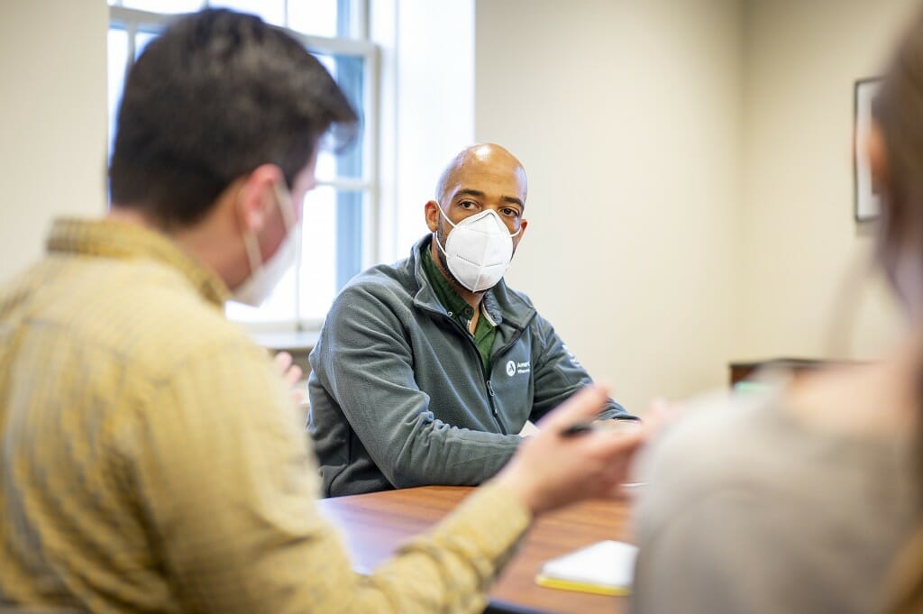 Barnes sitting at a table listening to a student