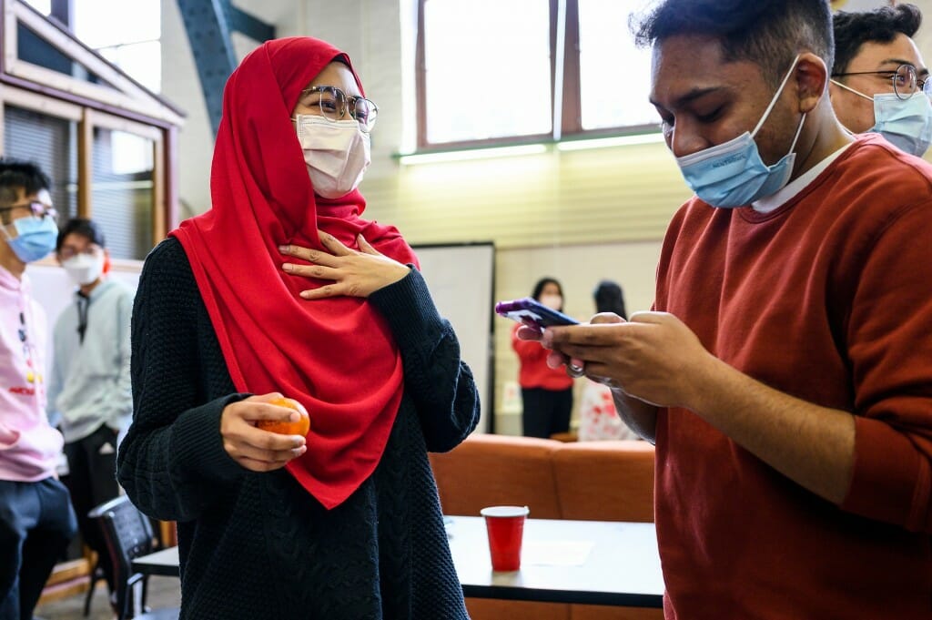 Aina Mohd Naser, left, and Imran Iskander talk while playing a matching game involving their names written on randomly shared Mandarin oranges.