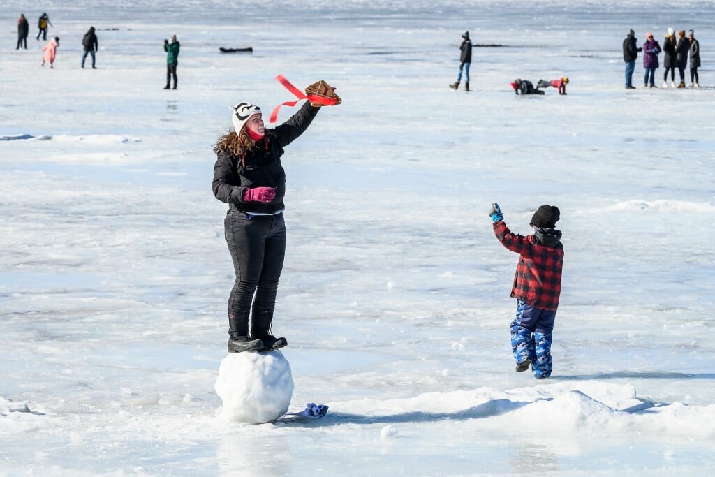Some hearty carnival goers launch a kite (crafted by hand at Wheelhouse Studios) over the frozen waters of Lake Mendota.