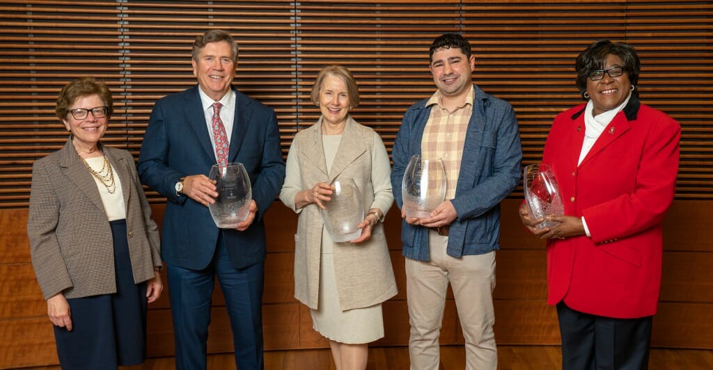 Award winners holding glass trophies