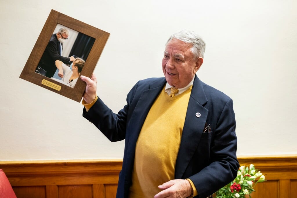 Thompson shows off a gift — a framed photograph depicting Thompson sharing an elbow-bump with a nursing student during a 2021 vaccine clinic tour.