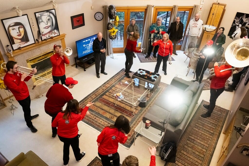 Band members form a circle around Wiley in his living room