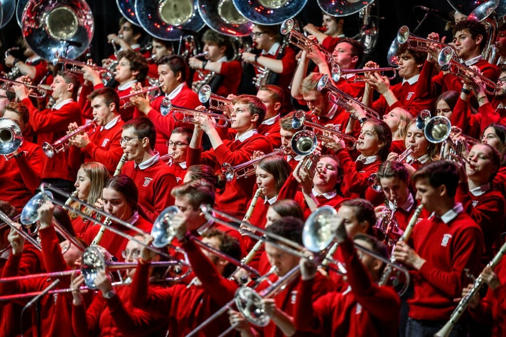Tubas, trumpets, clarinets, and trombones shine in the stage light as the band plays an opening song.
