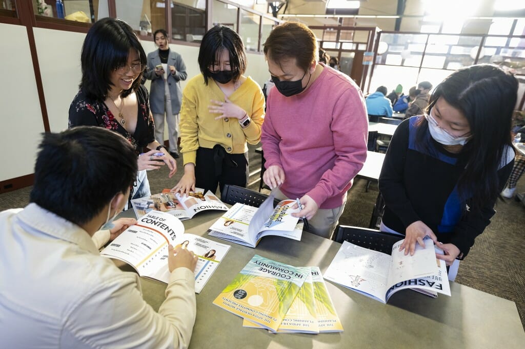 From left to right, students Ace Lo (with back to camera), Manola Inthavong, Emily Ren, Chee Meng Xiong and Qiuwen Quan look through the newest annual copy of the Asian Pacific Islander Desi American (APIDA) Heritage Month Planning Committee’s magazine.