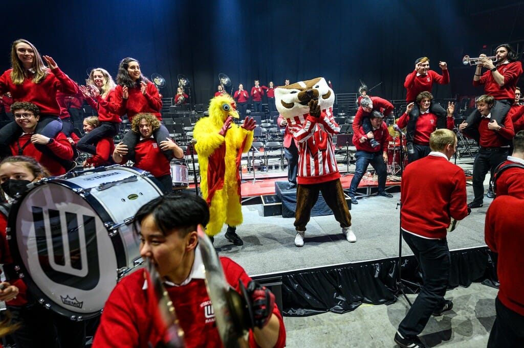 A person in a chicken suit and UW mascot Bucky Badger clap along to the song 