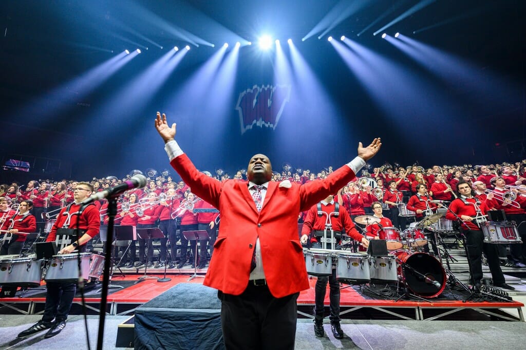 Band director Dr. Corey Pompey raises his hands to the unseen crowd in front of the UW Varsity Band.