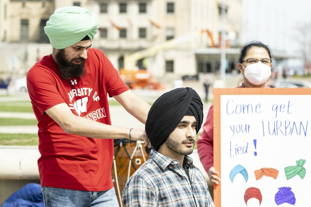 UW student Manmeet Singh Dang (left) ties a turban.