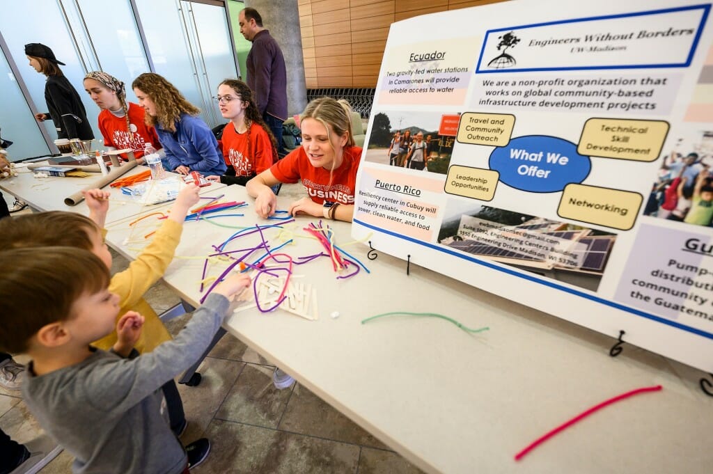 At right, Rachel Diel from the Discovery Center staff helps 3-year-old twins Belmont West (left) and Apollo West (right) make structures from pipe cleaners, popsicle sticks, and marshmallows at a table staffed by students from Engineers without Borders in the Discovery Building.