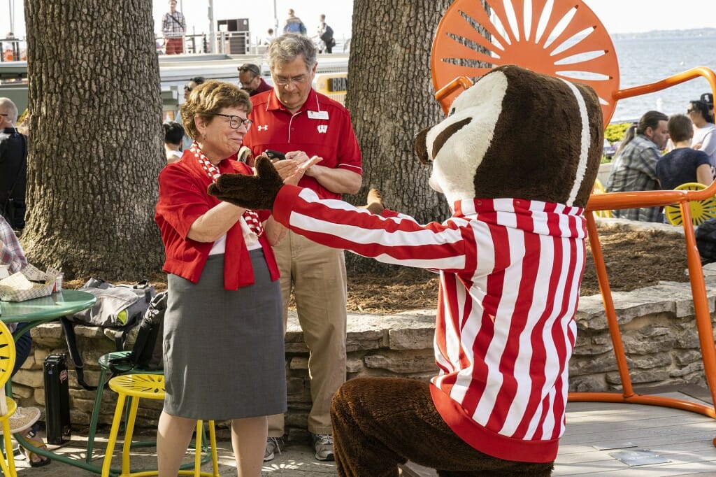 Bucky Badger on his knees, holding arms out to Becky Blank for a hug