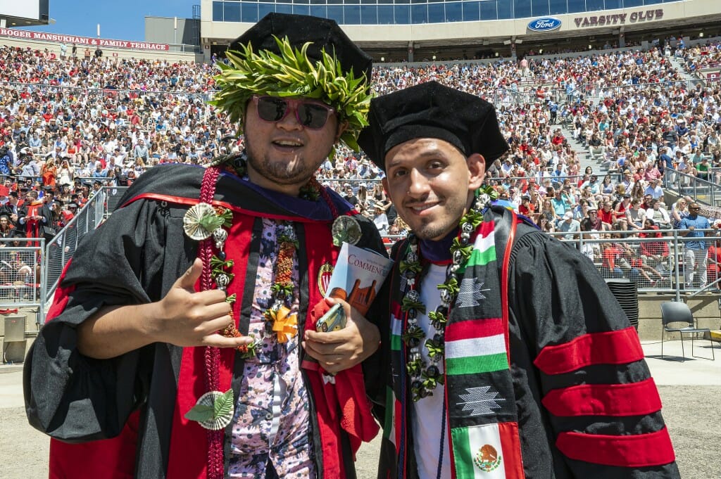 Two graduates in elaborately decorated caps and gowns