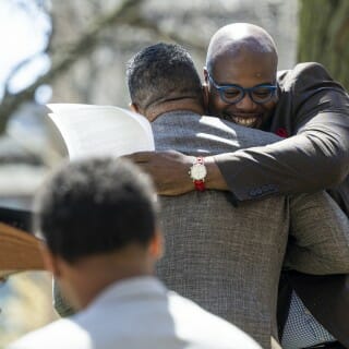 LaVar Charleston, Chief Diversity Officer at UW–Madison, hugs his friend Charles Holley, UW alum and donor, before he takes the stage during the Divine Nine Garden Plaza grand opening ceremony.