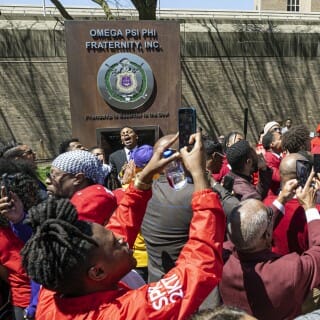Members of the Omega Psi Phi Fraternity, Inc., celebrate and take photos as their plaque is unveiled.