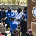 Members of the Phi Beta Sigma Fraternity, Inc., hold hands in celebration near their plaque in the Divine Nine Garden Plaza.