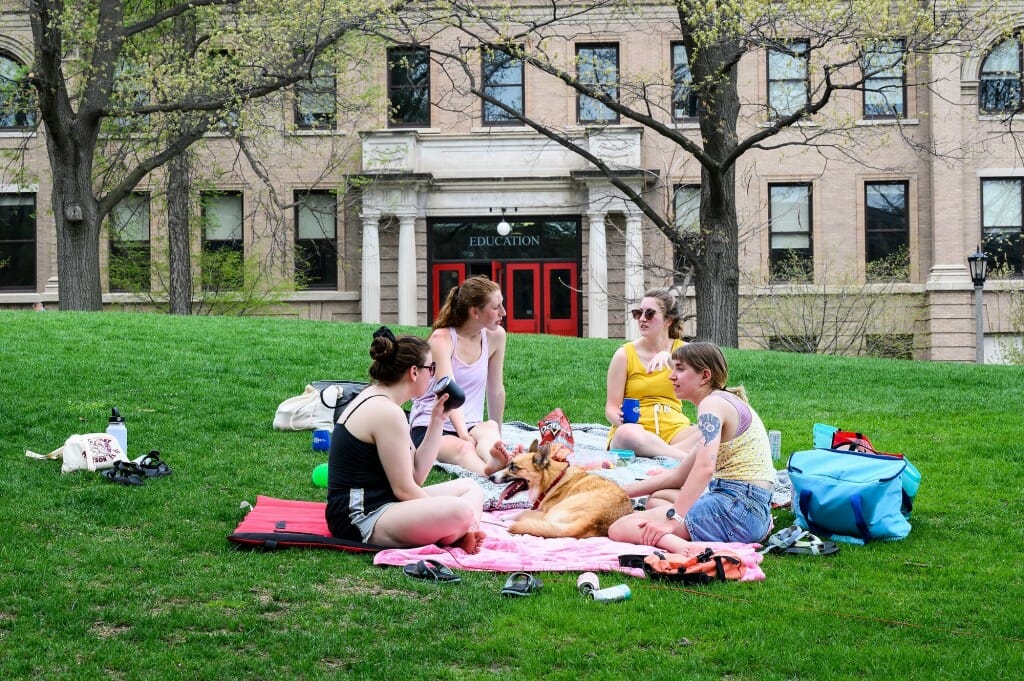 First-year audiology graduate students, from left to right, Vee Stanarevic, Jenny Lucke, Serena Helman, and Kelly Schneider along with Mia the dog enjoy a picnic on Bascom Hill on May 11.