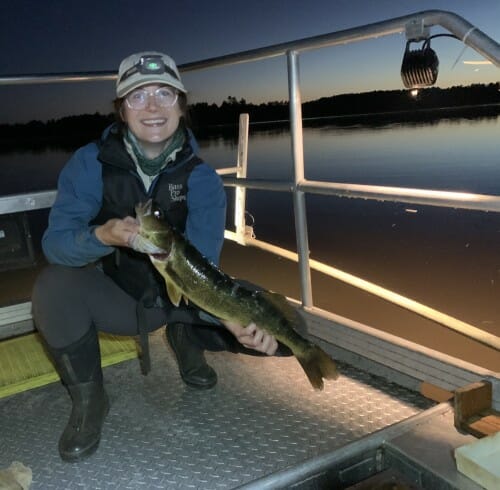 Holly Embke on a boat holding a walleye