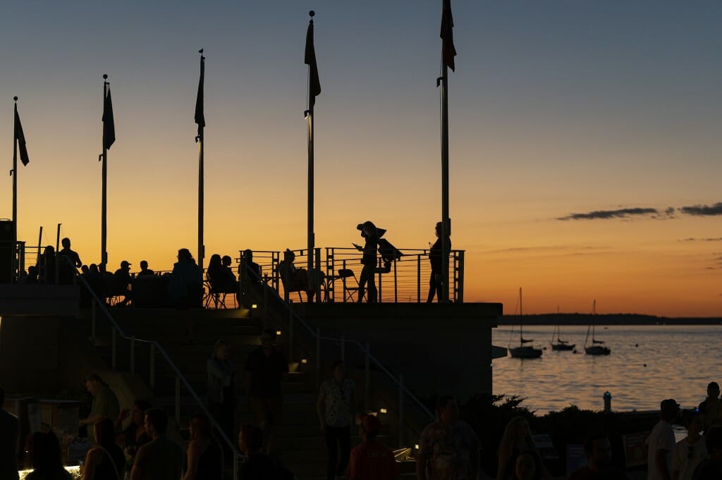 People silhouetted on a pier with sunset in background