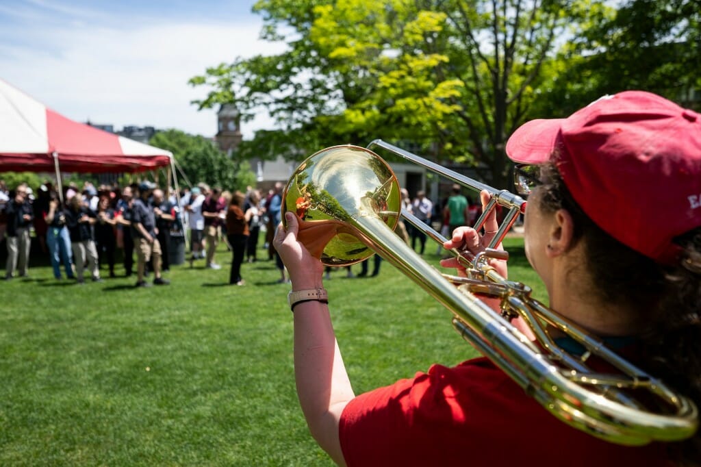 A person wearing red playing a trombone outdoors
