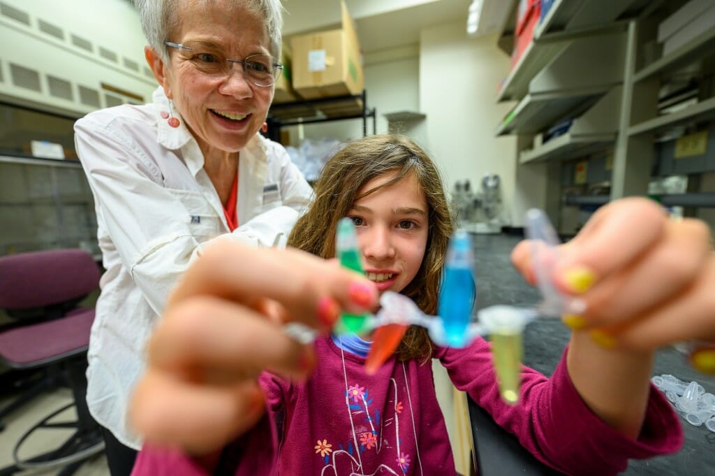 A woman and a young lady look at some colorful vials.