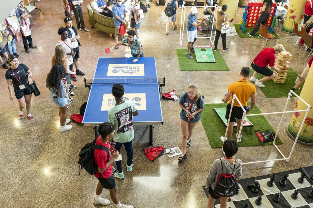 A view from above of students playing ping pong and others playing cornhole.