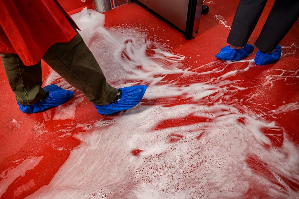 Staff members wear protective gowns and foot coverings as they walk through a foam cleanse before entering the processing plant in the Meat Science and Animal Biologics building.