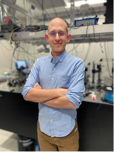 Goldsmith posing for a portrait, standing in his lab with his arms crossed