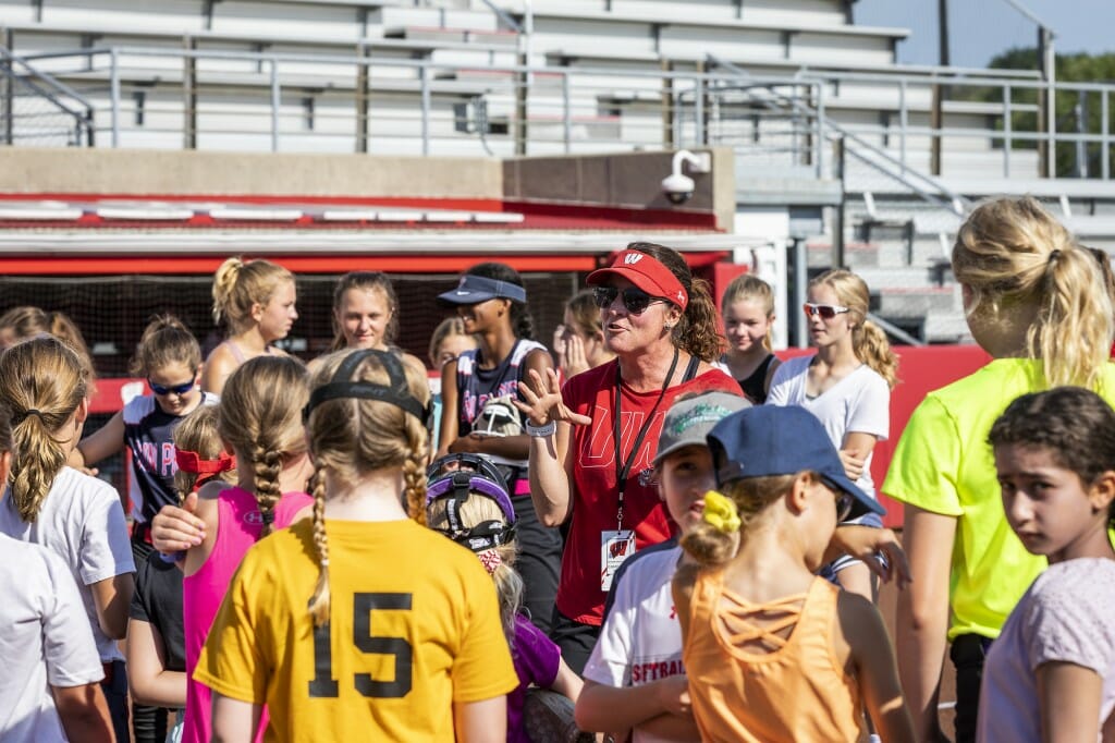 Kids at a softball camp for grades 2-8 listen to instructions from UW softball head coach Yvette Healy at Goodman Diamond.