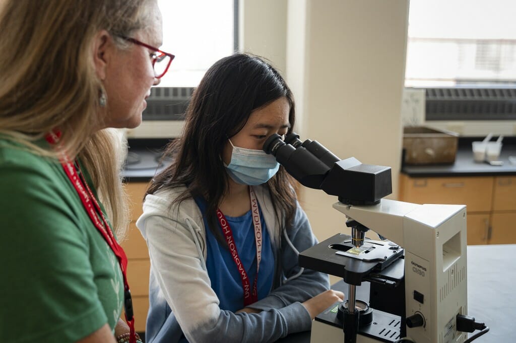 At a course in the Microbial Sciences Building on Aug. 1, Annette VanVeghel, forensic science instructor, teaches a student, Sabrina, about identifying fibers through a microscope. 