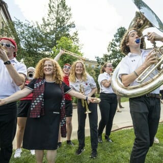 Chancellor Mnookin dances amid musicians playing their instruments, including a tuba.