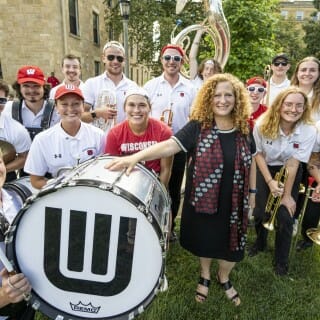 Chancellor Mnookin stands with some musicians holding instruments and a bass drum.