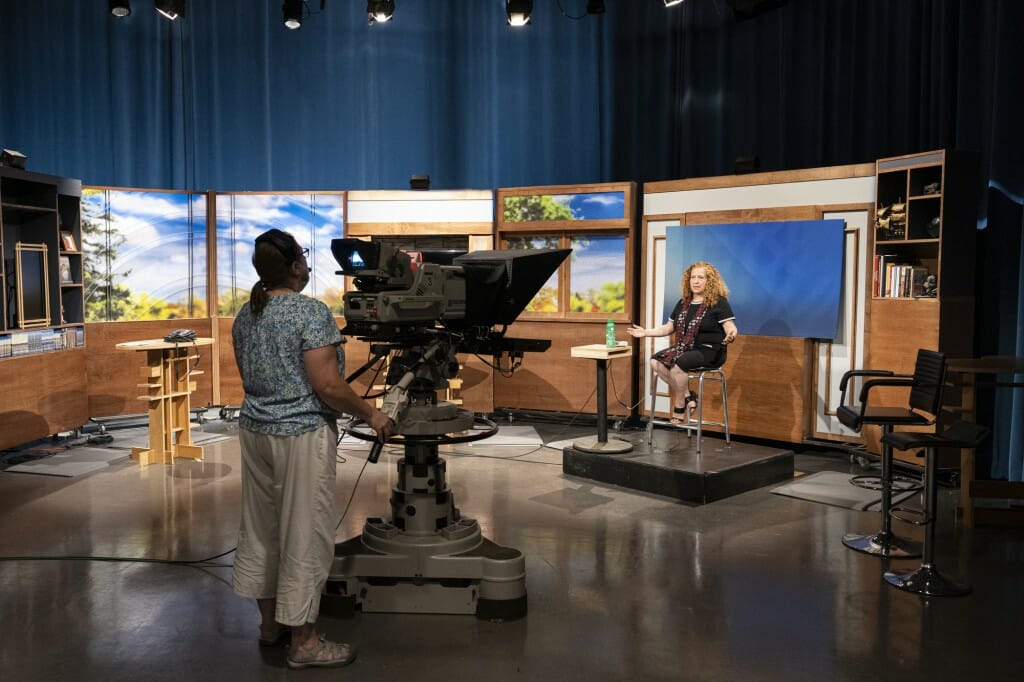 A cameraman points the camera at Chancellor Mnookin as she sits on the set.